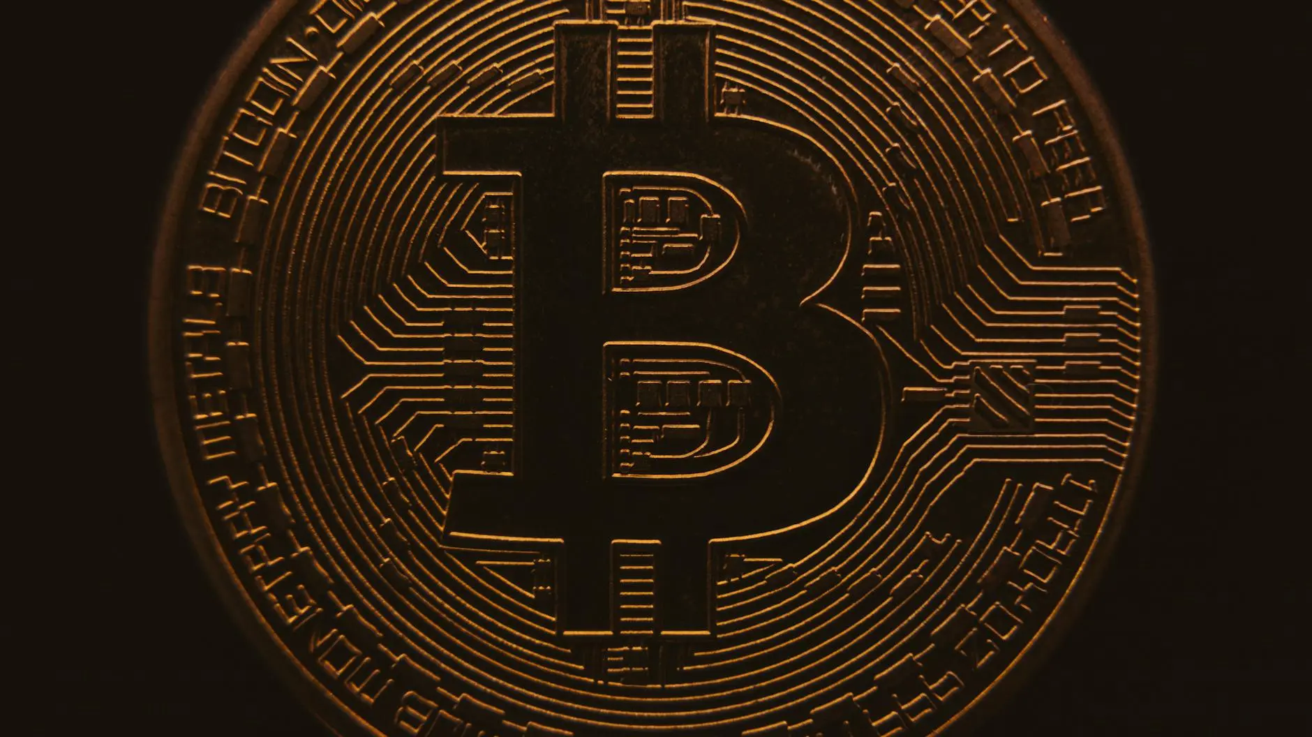 Close-up of a Bitcoin coin showing the symbol and circuit patterns.
