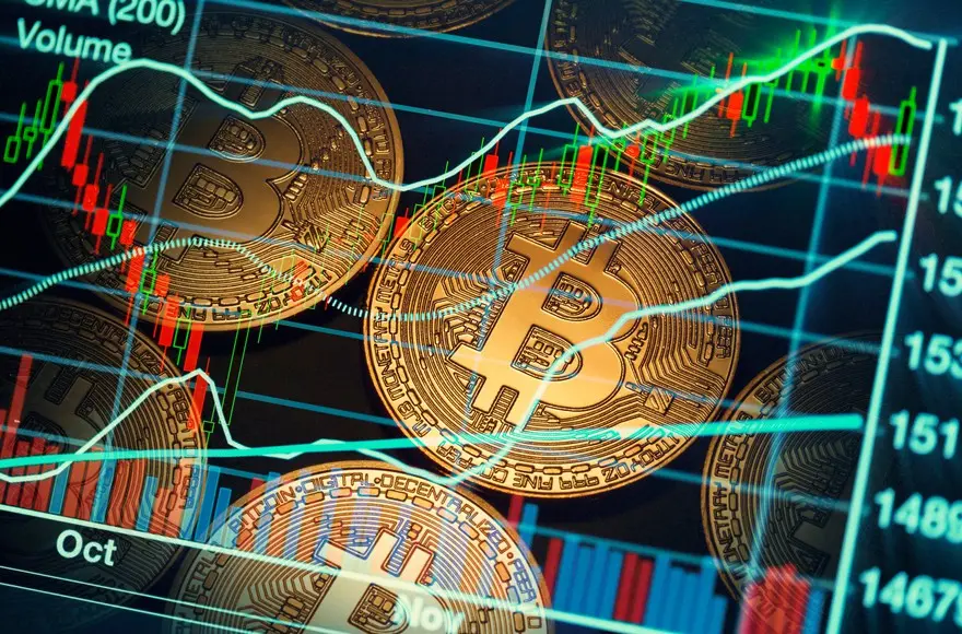Close-up of Bitcoin coins with trading graphs and charts in the background.