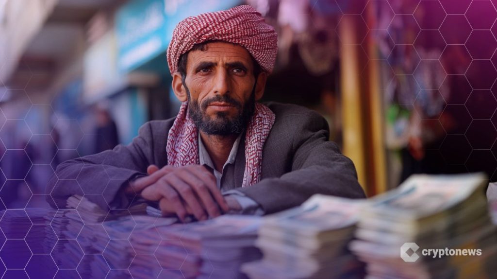 رجل يمني بثياب تقليدية يضع يديه على كومة من العملات النقدية
