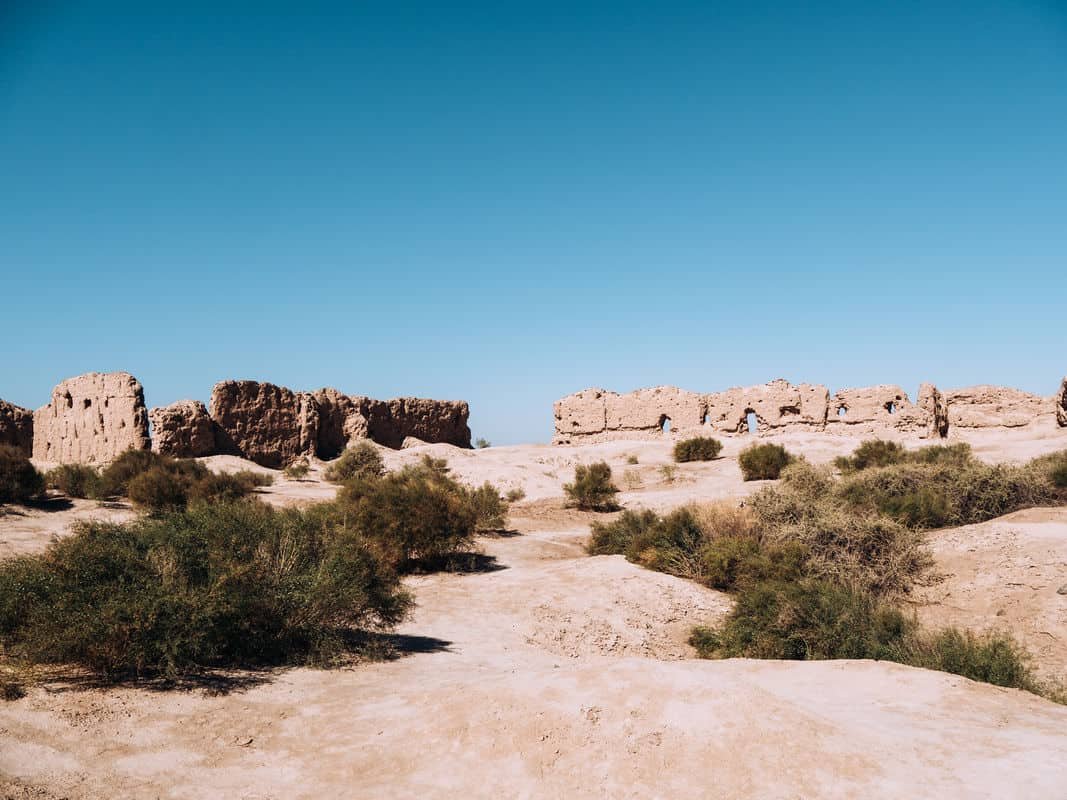 Ancient ruins on a dry sandy landscape under a clear blue sky.