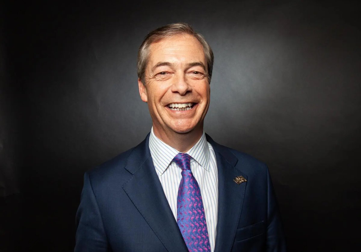 Photo of a smiling man in a blue suit with a colorful tie against a dark background.